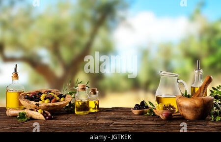 Frisch geerntete Oliven Beeren in Holz Schalen und kaltgepresstes Öl in Glasflaschen. Stillleben der Zubereitung von Speisen serviert auf alten Holzdielen. Kostenlose spac Stockfoto