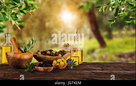 Frisch geerntete Oliven Beeren in Holz Schalen und kaltgepresstes Öl in Glasflaschen. Stillleben der Zubereitung von Speisen serviert auf alten Holzdielen. Kostenlose spac Stockfoto