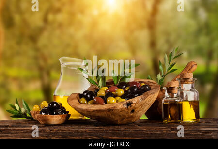 Frisch geerntete Oliven Beeren in Holz Schalen und kaltgepresstes Öl in Glasflaschen. Stillleben der Zubereitung von Speisen serviert auf alten Holzdielen. Kostenlose spac Stockfoto