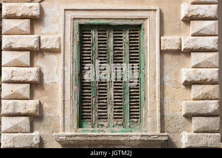Eine alte Fensterläden Fenster an einem Gebäude in Malta mit abblätternde Farbe grünen Stockfoto