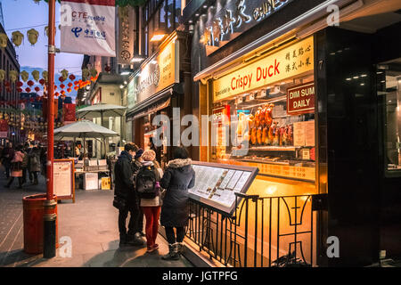 Touristen, die lesen Speisekarte an Bord außerhalb Chinatown Restaurant, London, England, UK Stockfoto