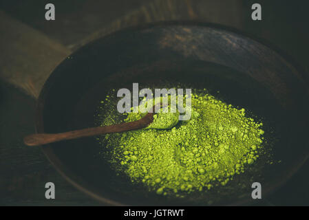 Japanische Matcha-Grüntee-Pulver in dunklen Holzschale mit Löffel, Tiefenschärfe, Textfreiraum, horizontale Komposition. Saubere, gesunde Ernährung, Diät-Lebensmittel Stockfoto