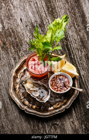 Ausgelöster Oyster Geldbußen de Claire und Bloody Mary cocktail auf grauem Hintergrund aus Holz Stockfoto