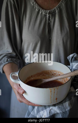 Eine Frau hält einen Topf mit hausgemachter Tomatenmarmelade Stockfoto