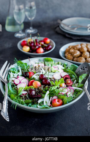 Kirsche Wildreis-Salat mit Hibiskus-Vinaigrette serviert mit Weißwein.  Auf schwarz/grau Hintergrund fotografiert. Stockfoto