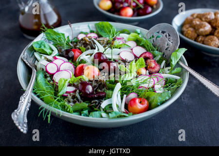 Kirsche Wildreis-Salat mit Hibiskus-Vinaigrette serviert mit Weißwein.  Auf schwarz/grau Hintergrund fotografiert. Stockfoto