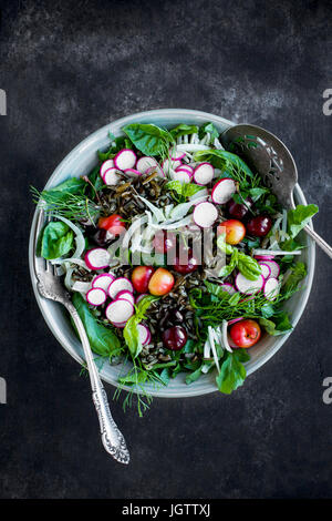 Kirsche Wildreis-Salat mit Hibiskus-Vinaigrette serviert mit Weißwein.  Auf schwarz/grau Hintergrund fotografiert. Stockfoto