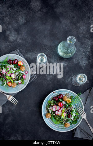 Kirsche Wildreis-Salat mit Hibiskus-Vinaigrette serviert mit Weißwein.  Auf schwarz/grau Hintergrund fotografiert. Stockfoto