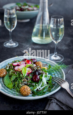 Kirsche Wildreis-Salat mit Hibiskus-Vinaigrette serviert mit Weißwein.  Auf schwarz/grau Hintergrund fotografiert. Stockfoto