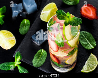 Frische Limonade mit Erdbeere, Limette und Minze auf dunklem Stein. Kalter Sommer Erdbeer Drink mit Minze und Eis. Erdbeer Mojito in Glas und Stockfoto