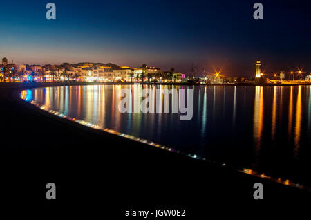 Gewässern der Nachtansicht von Rethymno Stadtzentrum, Hafen und Leuchtturm mit Reflexionen von bunten Lichtern im Mittelmeer, Kreta, Griechenland Stockfoto