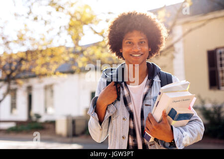 College-männliche Studenten tragen viele Bücher in College-Campus. Hübscher junger Mann mit Rucksack auf Straße. Stockfoto