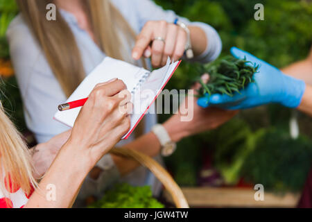 Junge Frau überprüfen kauft Liste. Mädchen mit einem Notebook in Händen. Einkaufsliste in der hand. Stockfoto