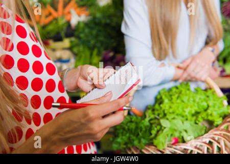 Junge Frau überprüfen kauft Liste. Mädchen mit einem Notebook in Händen. Einkaufsliste in der hand. Stockfoto