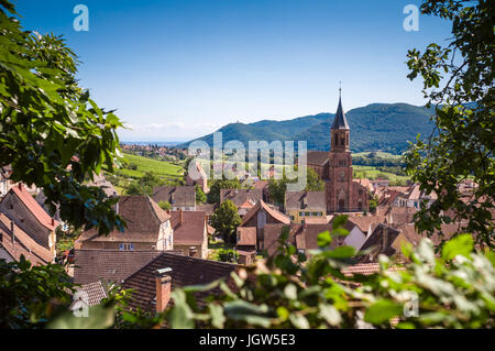 Panoramablick auf die typischen elsässischen Dorfes Wihr-au-Val mit Dächern, Kirche und Hügeln im Hintergrund Stockfoto