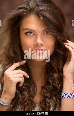 Porträt der jungen Frau mit langen lockigen Haaren, zeigt ihre Hände. Stockfoto