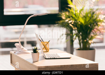 Arbeitsbereich mit Laptop-Computer in modernen leeren Büro mit Sonnenlicht Stockfoto