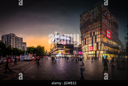 Einkaufen Vorplatz Uniqlo Gebäude voller Menschen in Sanlitun Peking bei Sonnenuntergang nach einem Gewitter Stockfoto