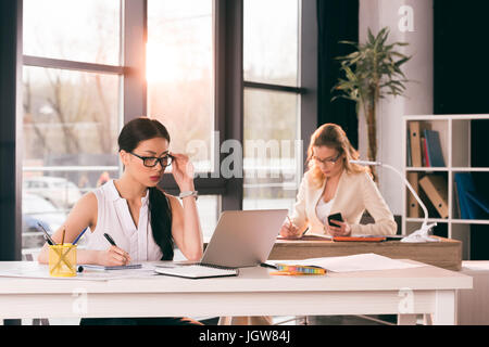 junge multiethnischen Geschäftsfrauen in festlich gekleidet im modernen Büro arbeiten Stockfoto