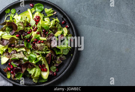 Blattsalat mit Granatapfel auf schwarze Platte, Schiefer-Hintergrund Stockfoto