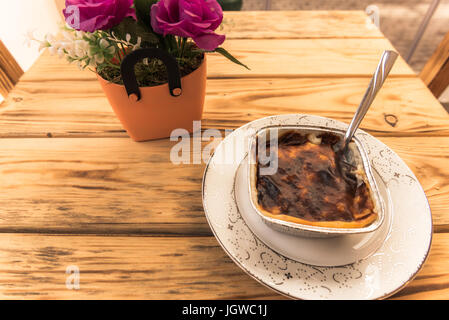 Türkische traditionelle Reis, Milch-puddings(sutlac), serviert auf einem Vintage Tisch mit alten Stühlen. Stockfoto