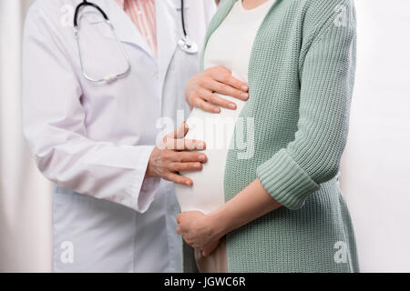 Schuss von Arzt untersucht schwangere Frau während ärztliche Beratung zugeschnitten Stockfoto