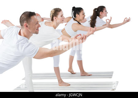 Seitenansicht der Gruppe junger Frauen mit Trainer stehen in Natarajasana Yoga-pose Stockfoto
