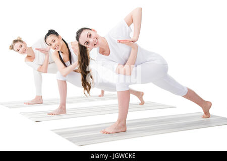 Lächelnde junge Frauen üben Variation der drehte sich Seite Winkel darstellen (Parivrtta Parsvakonasana) Stockfoto