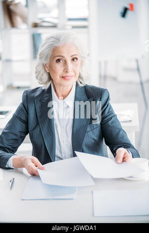 Porträt von zuversichtlich senior Geschäftsfrau Papierkram am Arbeitsplatz zu tun Stockfoto