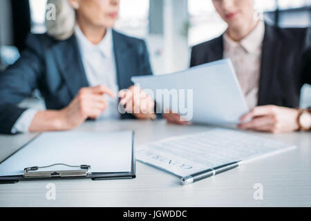 verkürzten Blick auf zwei Geschäftsfrauen diskutieren Geschäftsprojekt treffen im Büro, Zwischenablage und Objekt im Vordergrund Stockfoto