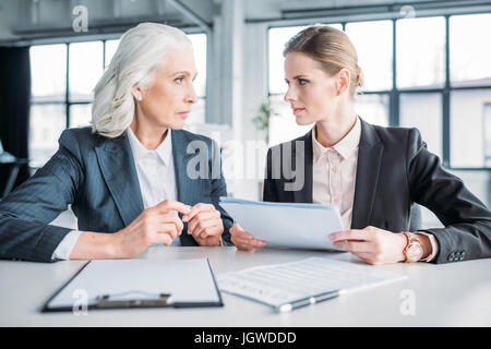 zwei schwere Geschäftsfrauen mit Dokumenten über Business-Projekt auf Sitzung im Büro Stockfoto