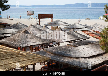 MAKARSKA RIVIERA, Kroatien - 20. Juni 2017: Sommer-Café am Strand der Adria Sea.Palm Baum Schirme schützen Touristen vor der Sonne am kroatischen Hot Stockfoto