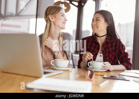 Schöne junge Frauen Kaffee trinken und mit Laptop im Café am Mittagessen treffen Stockfoto