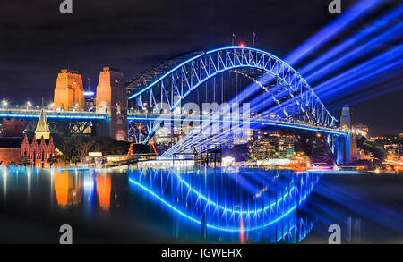 Sydney Hafen-Brücke bei vivid Sydney Lichterfest beleuchtet. Helle blaue Lichtstrahlen Projekt aus Übersee Passagierterminal in den Felsen-fr Stockfoto