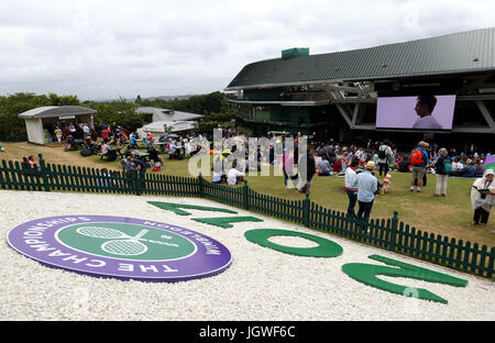 Zuschauern Schutz vor dem Regen am Tag acht der Wimbledon Championships in The All England Lawn Tennis and Croquet Club, Wimbledon. Stockfoto