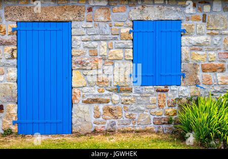 Vintage blaue Tür und Fenster an der Fassade von einer alten Steinmauer Hütte. Stockfoto