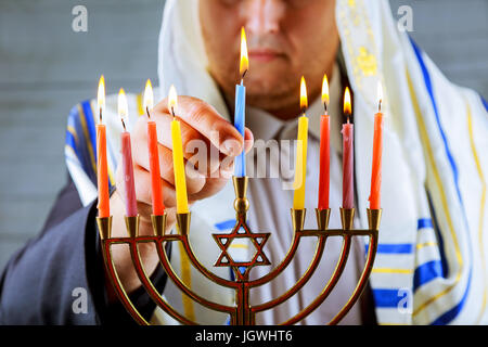 Mann Hand Anzünden von Kerzen in Menora am Tisch serviert für Chanukka Stockfoto