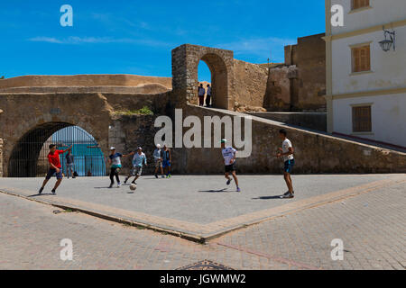 El Jadida, Marokko - 16. April 2016: Junger Mann Fußball spielen auf einem Platz in der Nähe der Mauern der Festung der portugiesischen Stadt (Cite Portugaise) Stockfoto