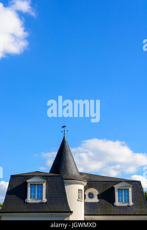 Schieferdach für eine hoch stehende Haus mit einem Turm und einer Wetterfahne unter blauem Himmel. Stockfoto