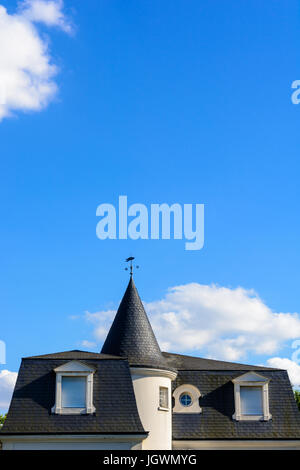 Schieferdach für eine hoch stehende Haus mit einem Turm und geschlossenen Fensterläden unter blauem Himmel. Stockfoto