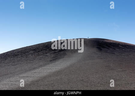 Eine Person steht mit Armen weit offen auf Inferno Kegel im Krater des Moon National Monument & bewahren, Idaho, USA Stockfoto