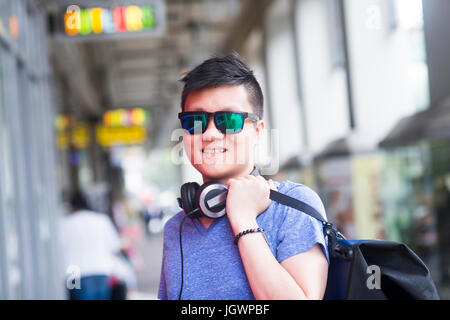 Porträt des Mannes mit Kopfhörer mit Blick auf die Kamera zu Lächeln Sonnenbrille Stockfoto