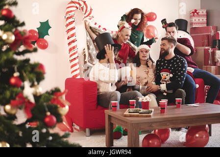 Junge Erwachsene Freunde versuchen auf Partyhüte Christmas Party Stockfoto