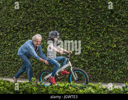 Großmutter Enkel auf seinem Fahrrad schieben Stockfoto