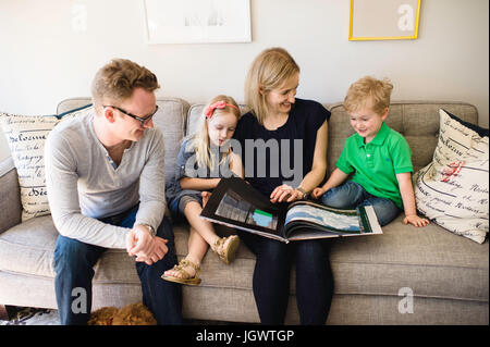 Eltern auf Sofa lesen Märchenbuch, Sohn und Tochter Stockfoto