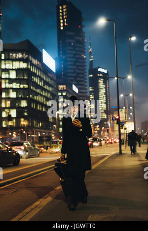 Geschäftsfrau mit Handy und ziehen Trolley Gepäck, Mailand, Italien Stockfoto