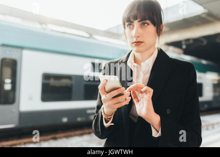 Geschäftsfrau mit Handy in Nähe des Bahnhofs, Mailand, Italien Stockfoto