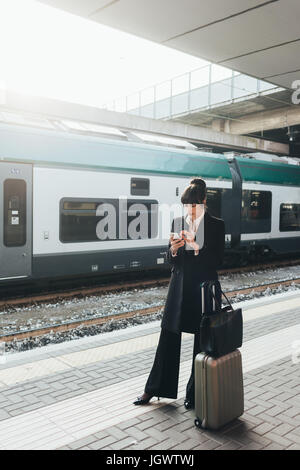 Geschäftsfrau mit Handy in Nähe des Bahnhofs, Mailand, Italien Stockfoto