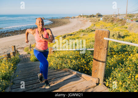 Junge Frau, die sich fit halten, erhöhte läuft Treppen in der Nähe von Strand, Ansicht Stockfoto