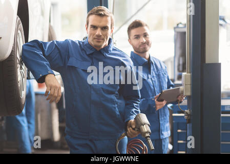 Unsere eigene Werkstatt. Erfolgreiche fleißige Mechaniker ihre Arbeit Pflege ein Auto und läuft eine Diagnose für ihre Kunden tun erfahren Stockfoto
